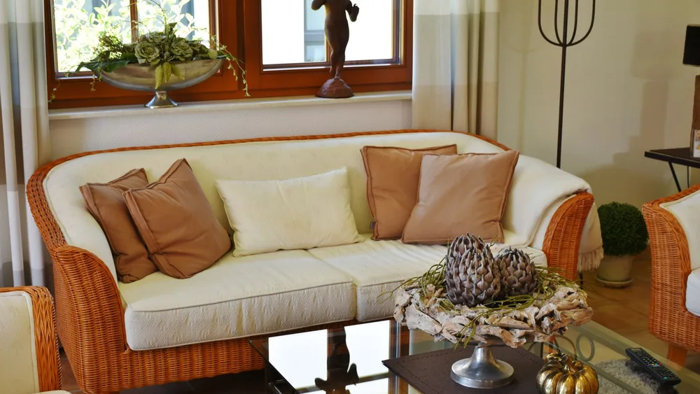 Elegant living room featuring a wicker sofa, cushions, and artistic decor pieces.