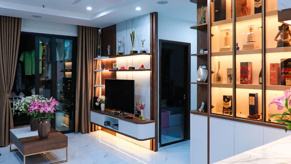 Sleek modern living room with illuminated shelves, TV unit, and floral decor.