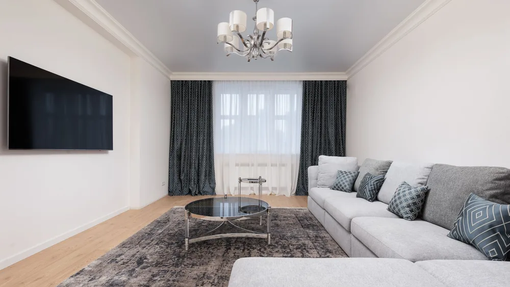 Contemporary living room with decorative cushions on sofa against table and TV with black screen in house