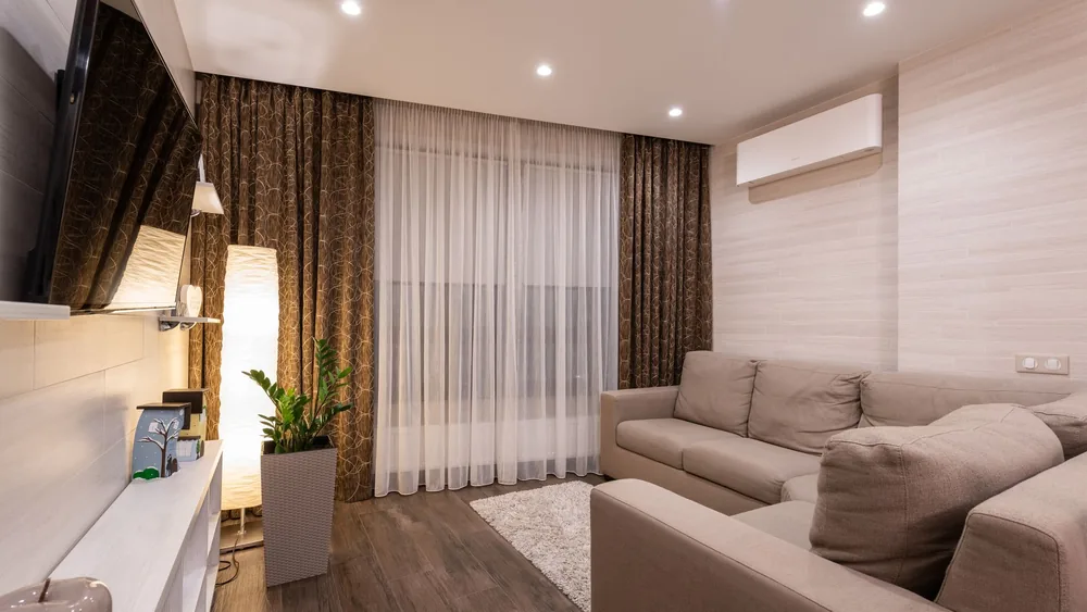A stylish and cozy living room featuring a sofa, wooden flooring, and soft lighting.