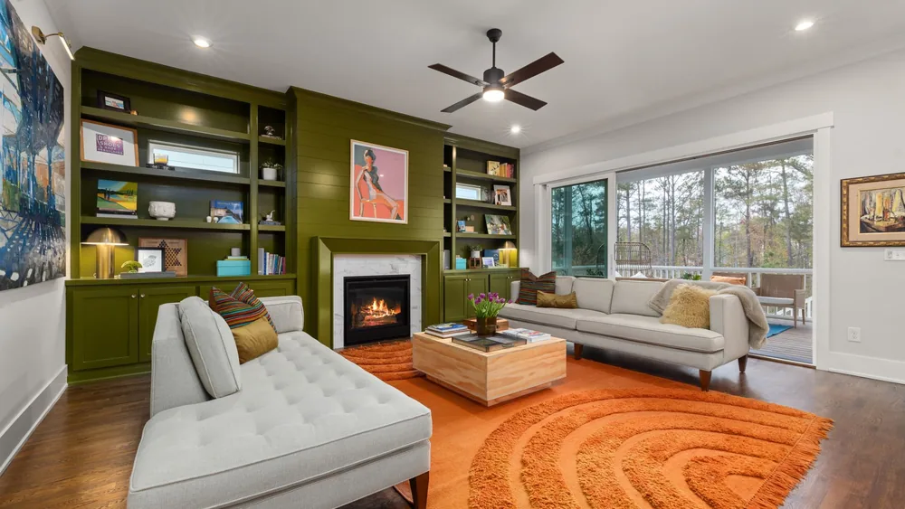 Contemporary living room with green bookshelves, fireplace, and elegant furnishings.
