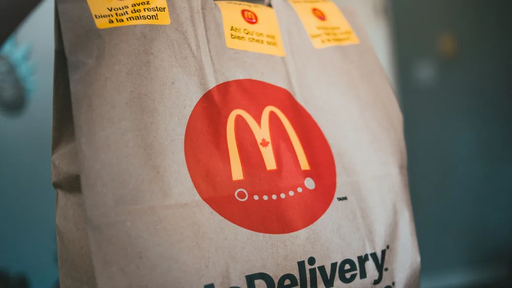 Paper packet with tasty fresh hot fast food on blurred background in restaurant