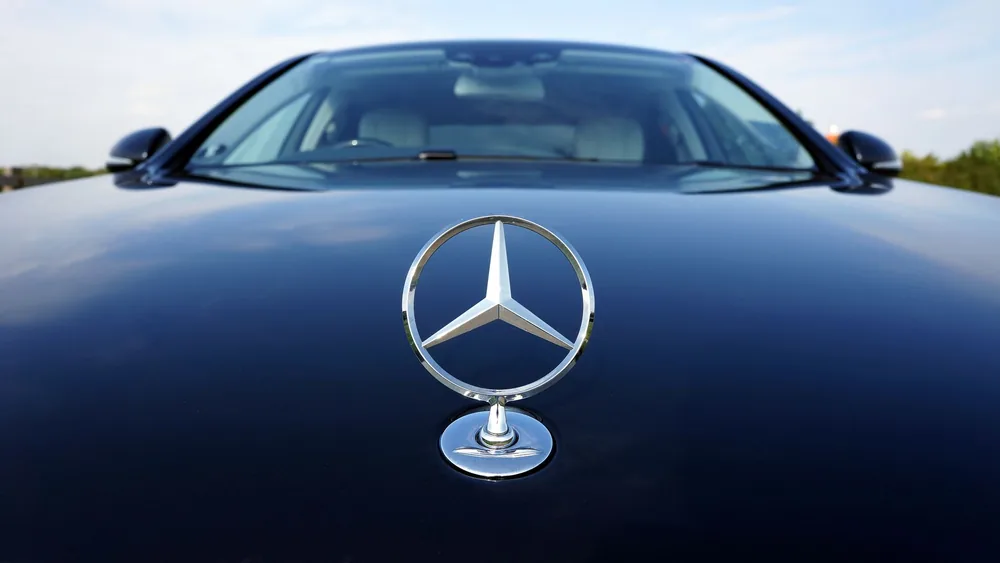 Close-up of a Mercedes-Benz emblem on a luxury car hood featuring a sleek design.