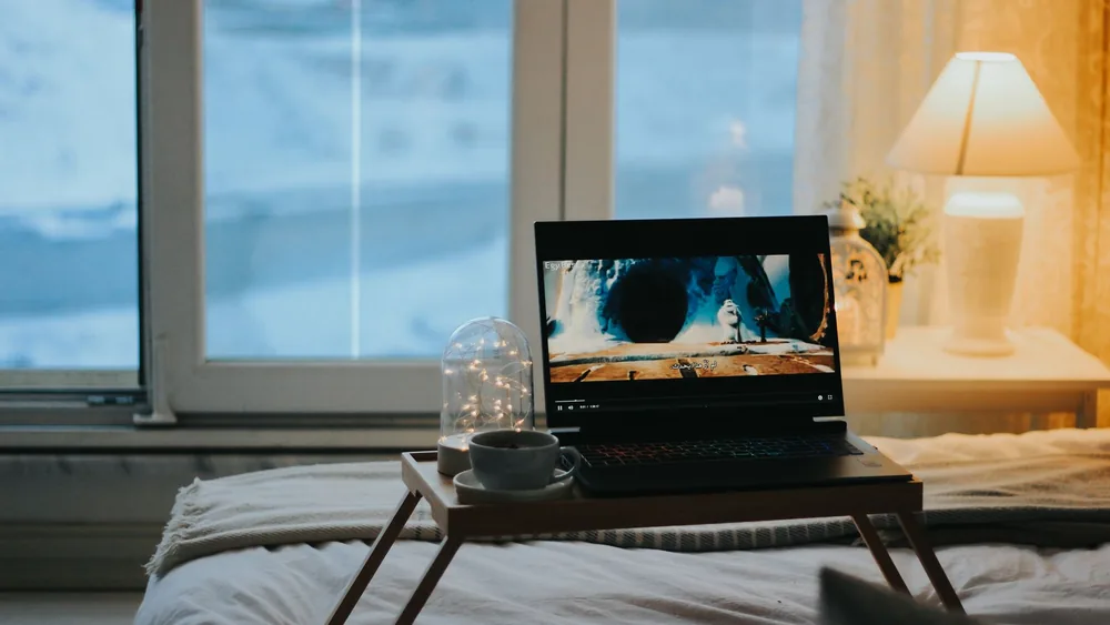 Relaxing bedroom scene with a laptop on a tray table, perfect for a cozy night in.