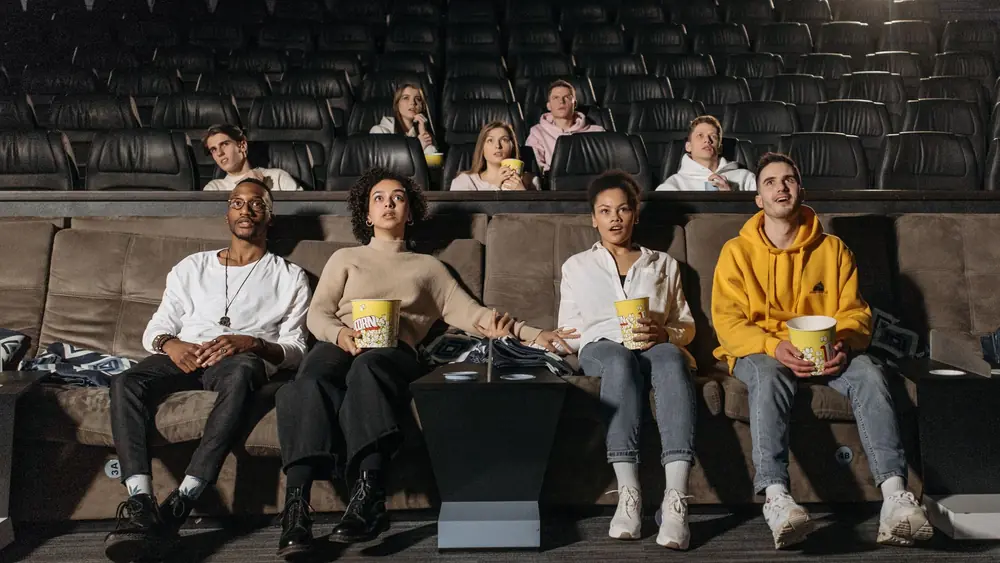 A diverse group of people enjoying a suspenseful movie scene in a theater.
