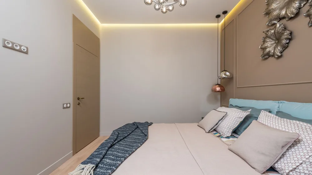 Interior of a bedroom with a made bed, pillows and blanket