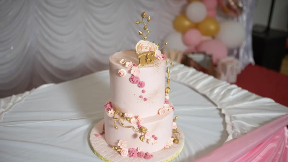 Beautifully decorated pink cake with floral design for an 18th birthday celebration, perfect for parties.