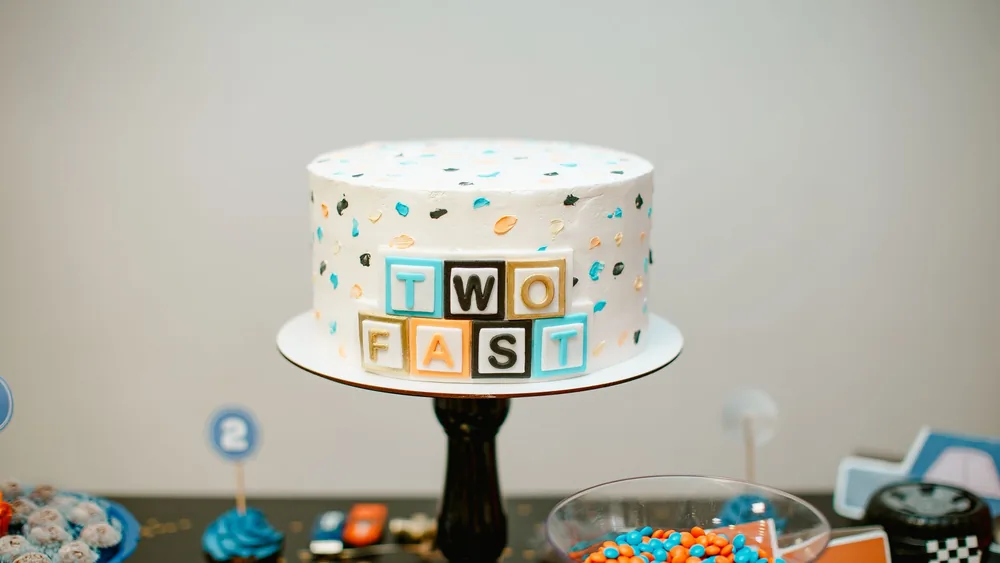 Colorful 'Two Fast' themed cake at a racing birthday party setup.