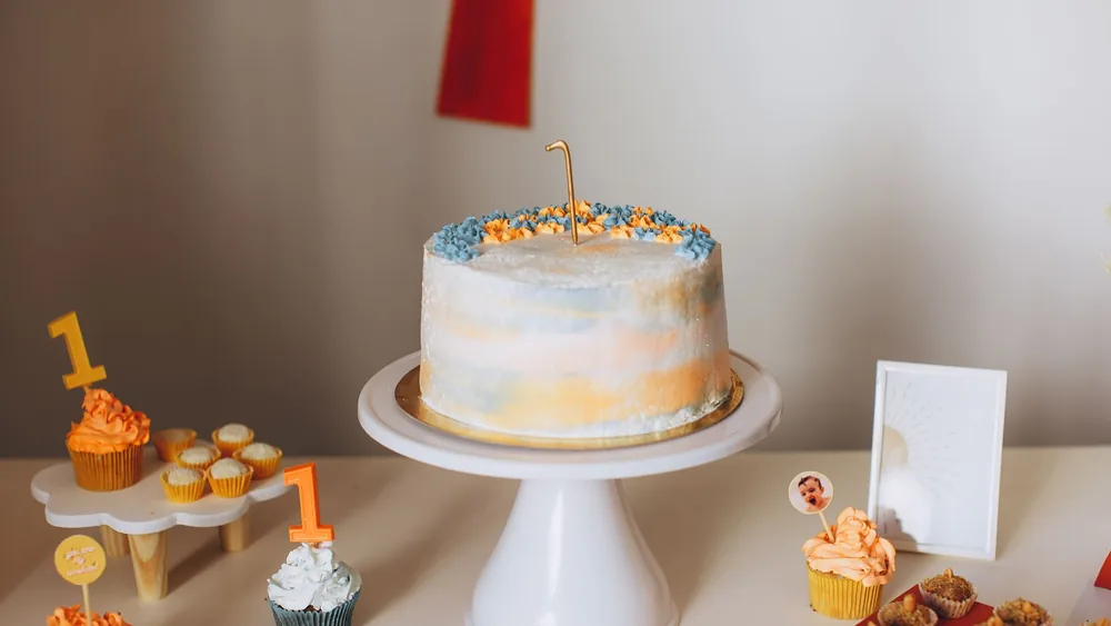 A beautifully decorated cake with cupcakes for a first birthday celebration.