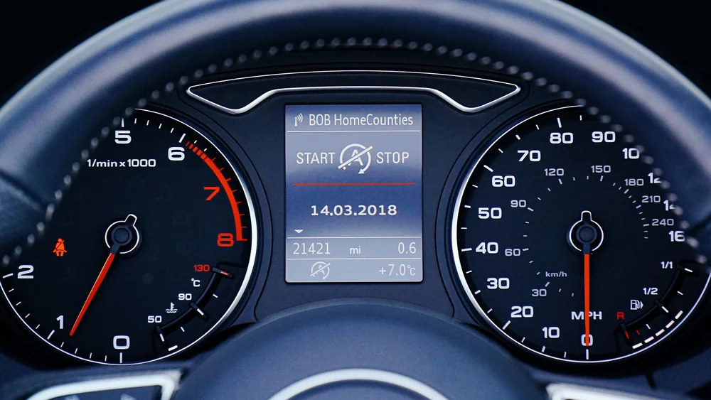 Close-up of a car dashboard displaying speedometer, tachometer, and digital display with mileage.