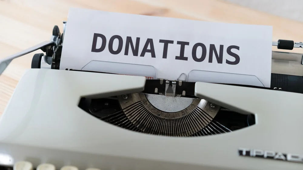 Close-up of a vintage typewriter with a paper displaying the word 'DONATIONS'.