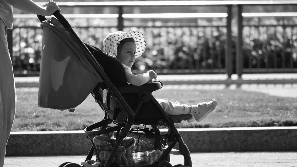 Adorable baby in a sun hat enjoys a stroll in a stroller, black and white urban setting.