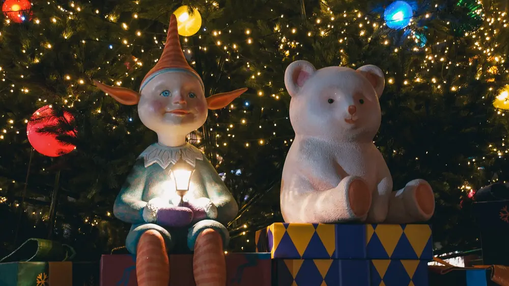 A charming holiday scene with elf and bear decorations amidst Christmas lights in Kyiv, Ukraine.