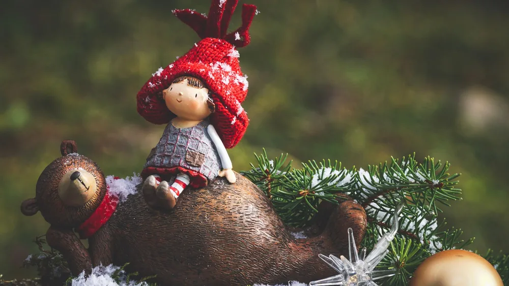 Charming winter scene featuring a toy elf and bear in snow with festive decorations.