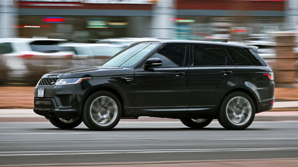 A black SUV speeds through a busy Toronto street, showcasing its elegance and power.