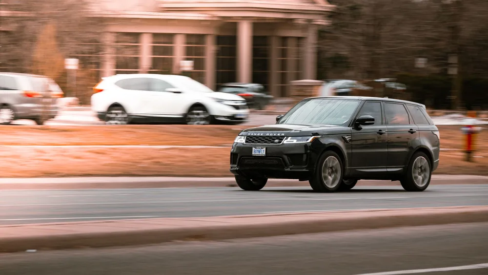 A luxury Range Rover speeding on a city street in Canada, captured with motion blur highlighting its velocity.