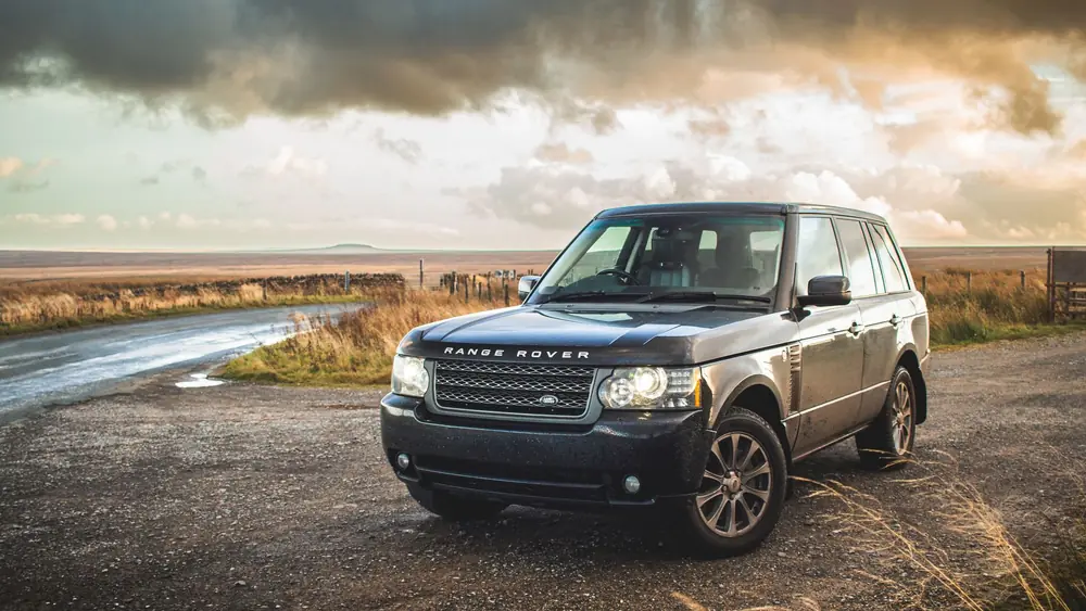 A stylish Range Rover parked on a rural road with dramatic skies.