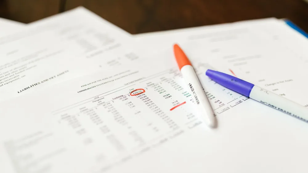 Close-up of financial documents with pens highlighting important data points.
