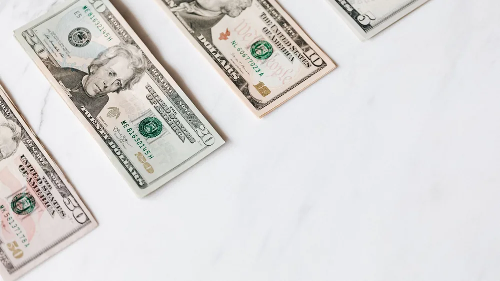 From above of US dollar banknotes in different denominations placed in row on white surface