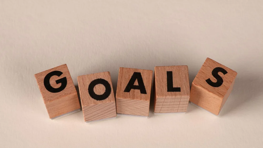 Aligned wooden blocks spelling 'Goals' symbolize target achievement and ambition.