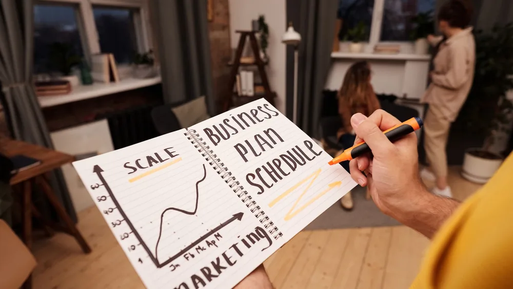 Person holding a notebook with planning details and graph for business strategy indoors.