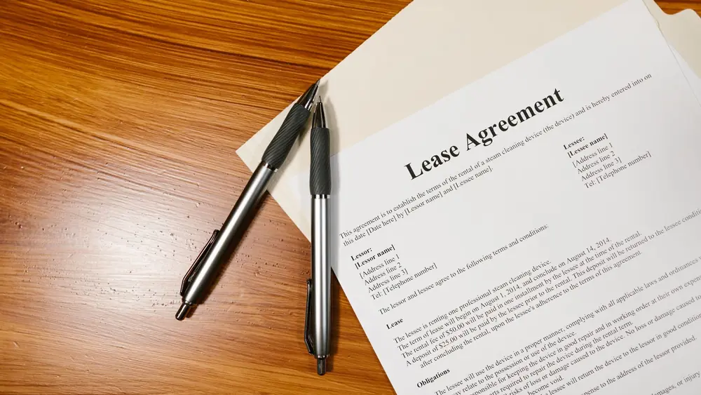 High-angle view of a lease agreement and pens on a wooden desk.