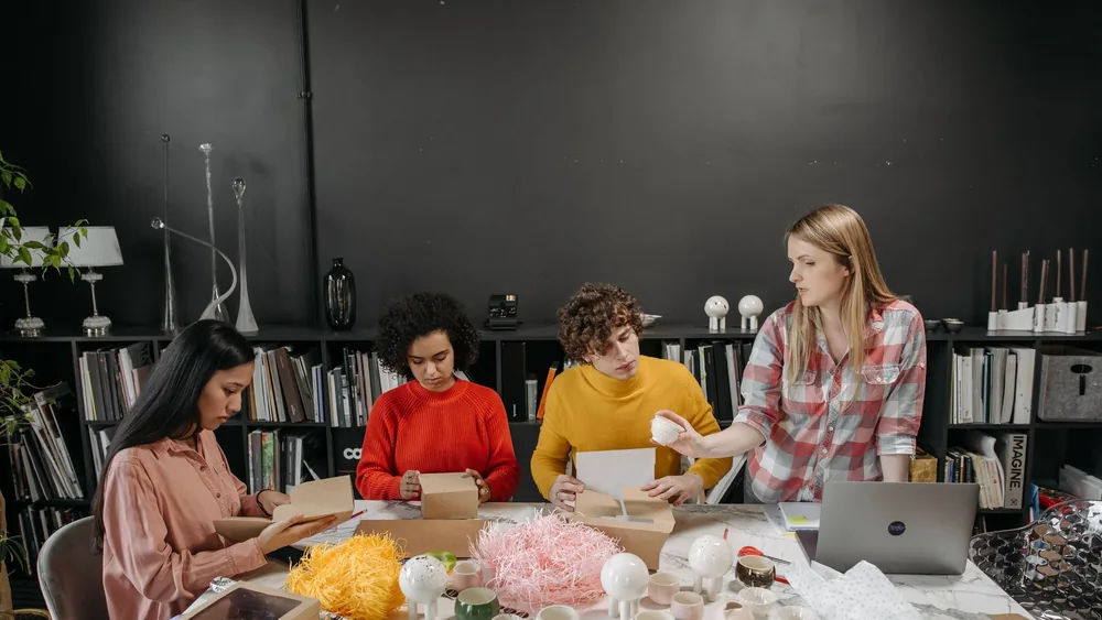 Four adults engaged in a creative ceramics project at a modern workspace.
