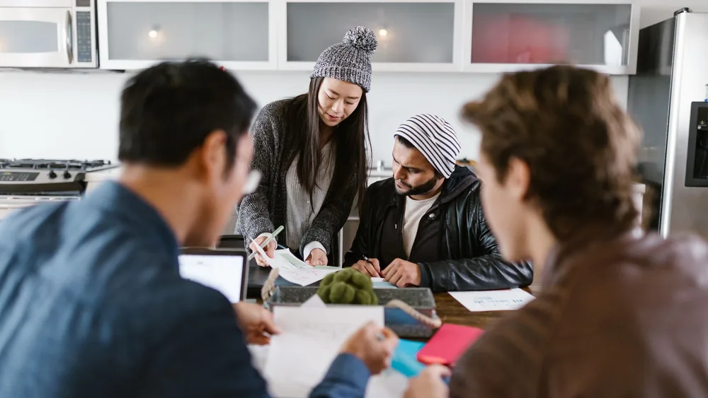 A dynamic group of young entrepreneurs brainstorming in a well-lit office space.
