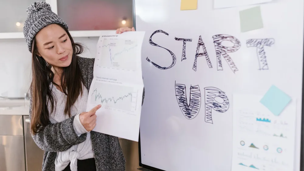 Asian woman presenting business growth charts during a startup pitch indoors.
