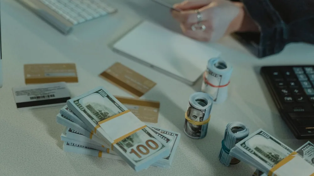 Close-up of dollar bills and credit cards on a desk, symbolizing financial transactions.