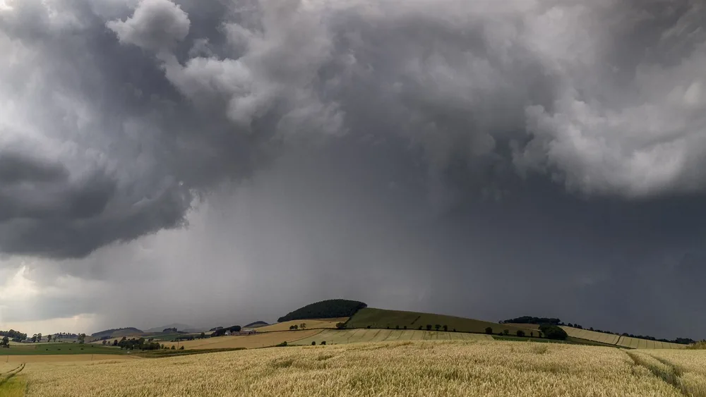 Dramatic storm clouds roll over golden wheat fields under a tumultuous sky.