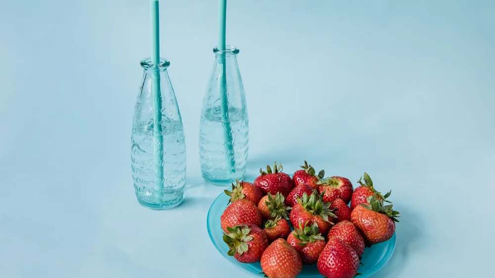 A vibrant composition of strawberries on a plate with bottled water, perfect for refreshing summer themes.
