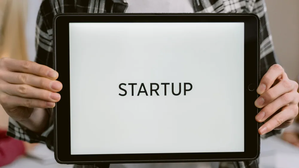 Person holding a digital tablet displaying the word 'STARTUP', representing new business concepts.