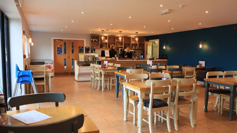 A cozy and modern café interior in England with wooden tables and bright lighting.