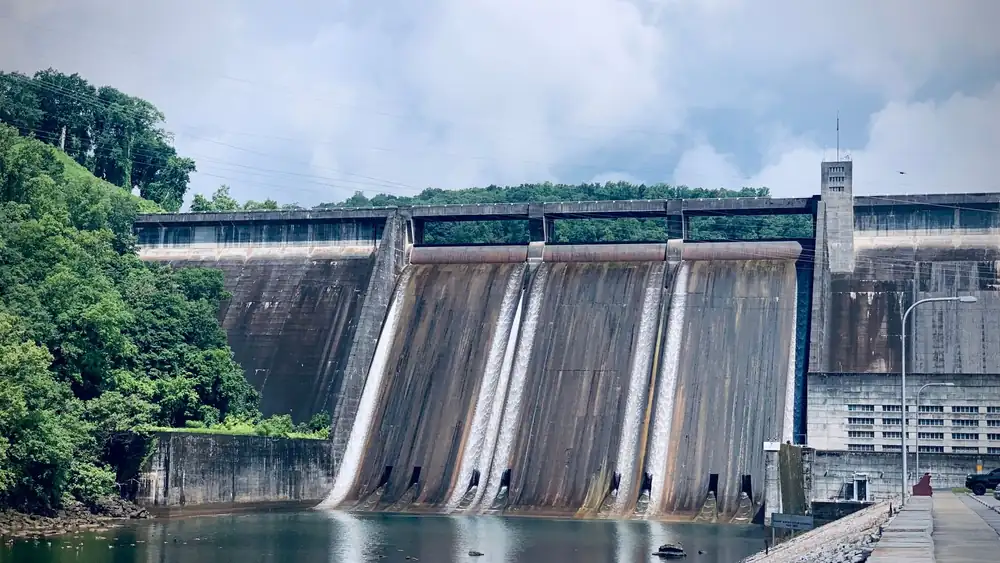 Scenic view of a hydroelectric dam in Andersonville, Tennessee with water cascading down and lush greenery.