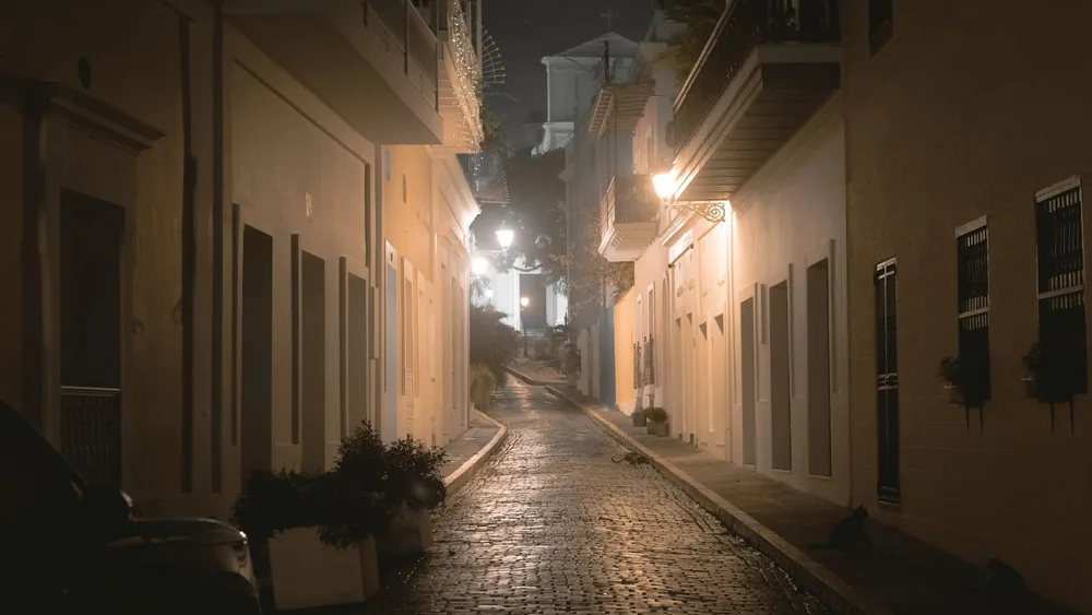 Explore the atmospheric charm of a narrow street in Old San Juan at night, showcasing historic colonial architecture.