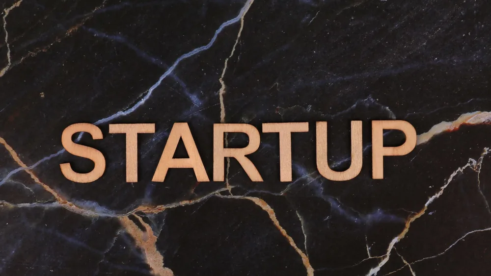Wooden letters spelling 'STARTUP' on a dark marble background, symbolizing business innovation.