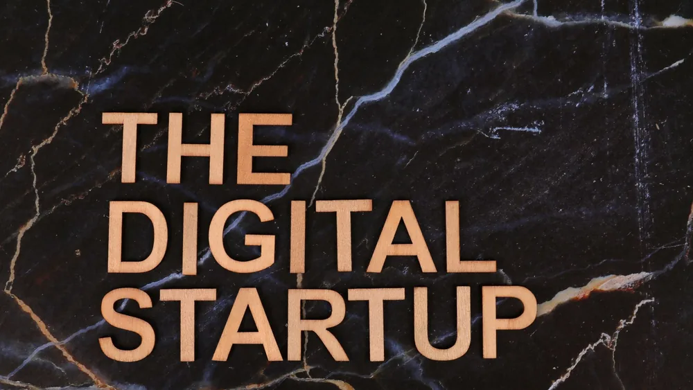 Wooden letters spelling 'The Digital Startup' on a dark marble background. Ideal for business and tech themes.