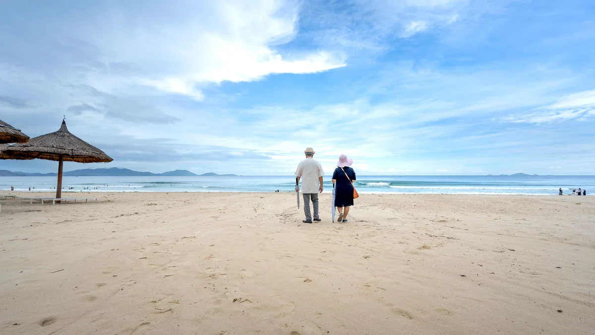 An older couple walking on a beach while on holiday