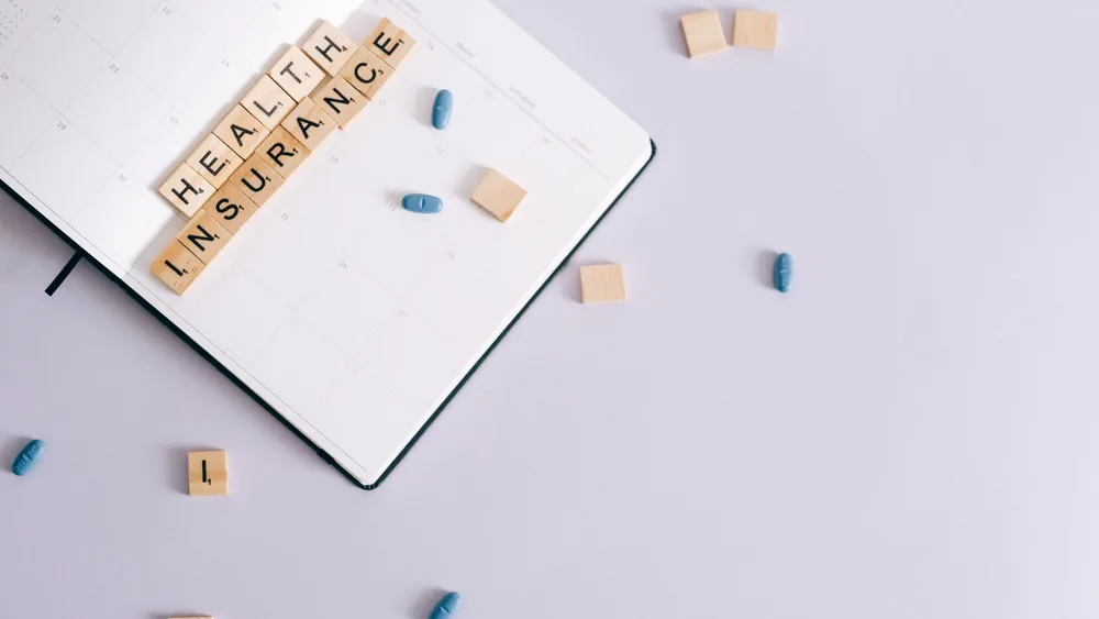 Flat lay of health insurance concept with planner and pills.