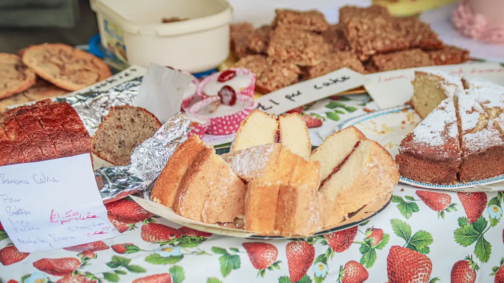 A variety of homemade cakes on a colorful table at a market stall.