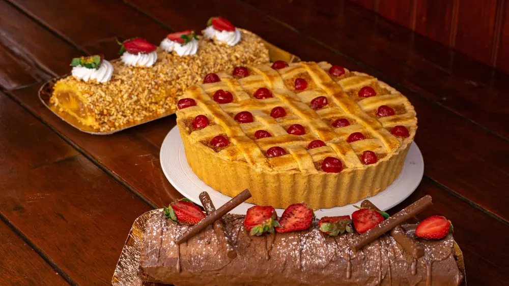 A variety of delectable homemade cakes and tarts displayed on a rustic wooden table, perfect for dessert lovers.