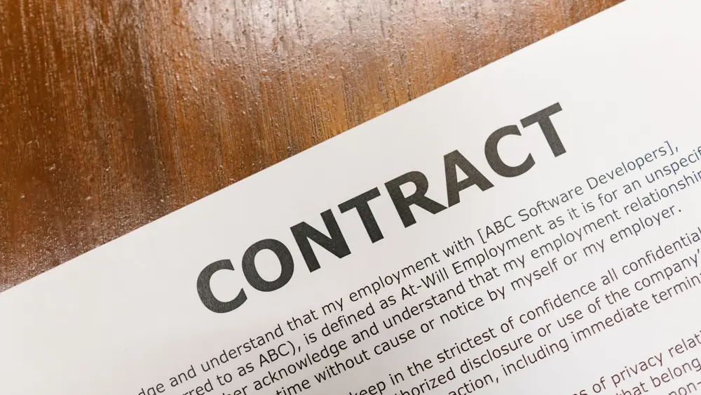 A detailed close-up of a printed contract document on a wooden table surface.