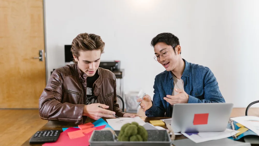 Two business professionals discuss ideas and strategies in an office setting, fostering innovation and teamwork.