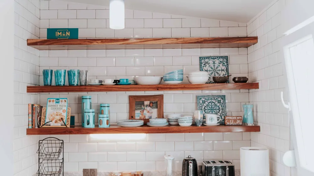 Stylish kitchen with open wooden shelves displaying tableware and decor.