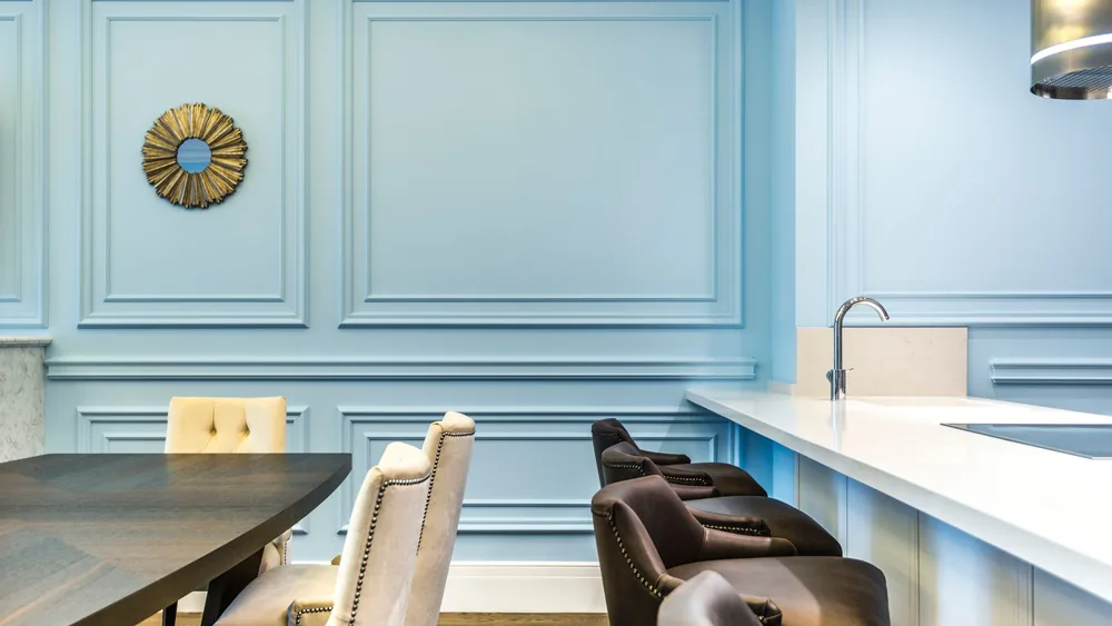 Stylish dining room featuring modern furniture, soft blue walls, and a sleek countertop.