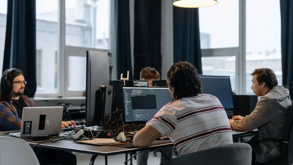 Team of developers working together on computers in a modern tech office.