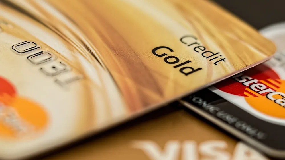 Stack of various branded credit cards focusing on gold card showing finance and cashless concept.