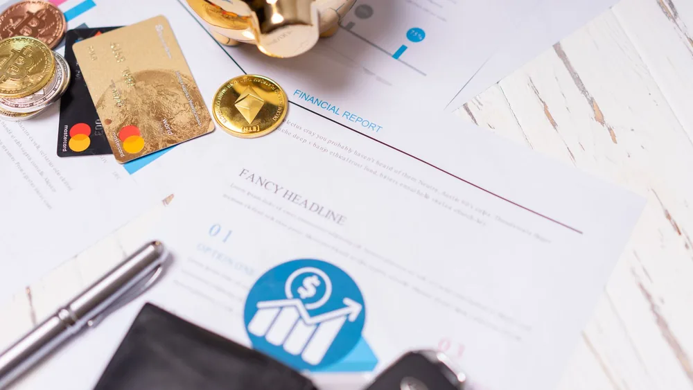 Close-up of financial documents, credit cards, coins, and a pen on a wooden desk.