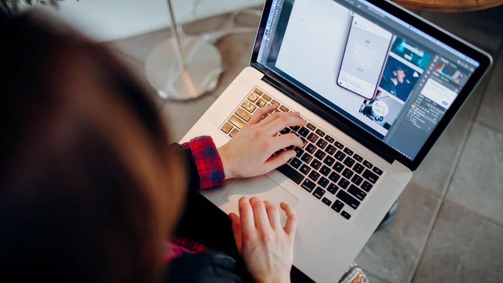 Close-up of a person working on a laptop with graphic design software.